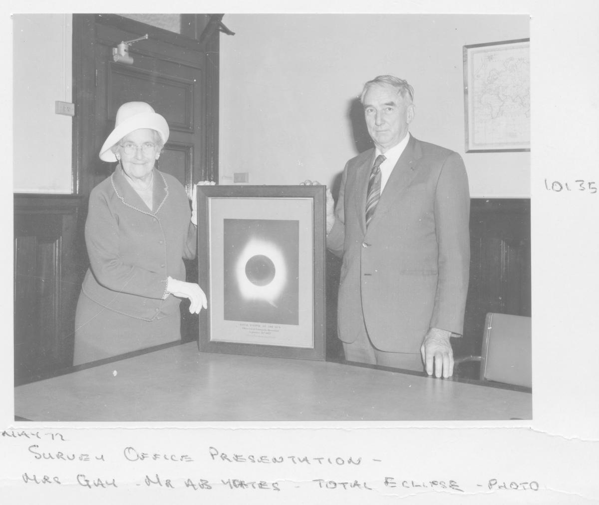 Survey Office presentation: Mrs Gay and Mr Yates holding a photograph of a total sun eclipse - Brisbane, May 1972