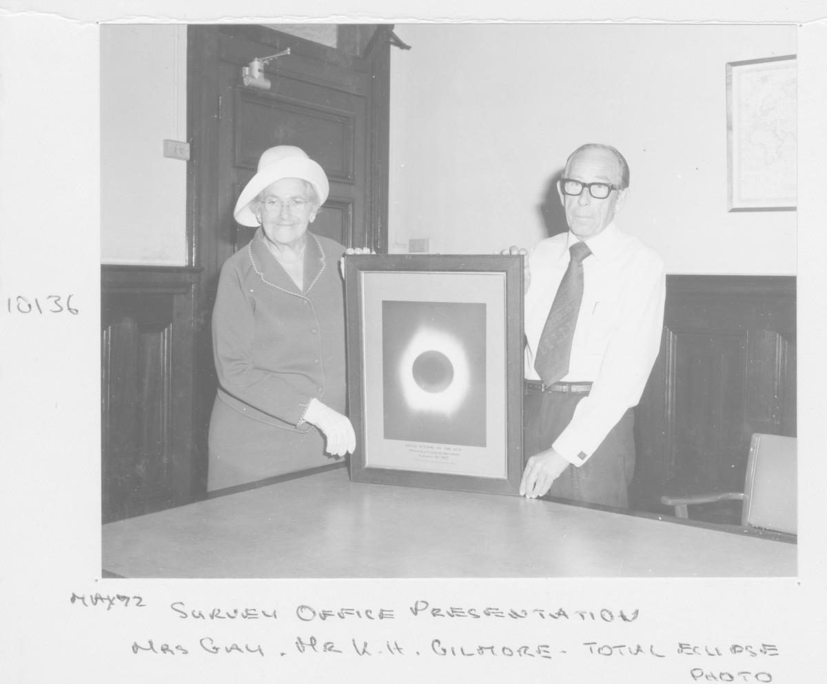 Survey Office presentation: Mrs Gay and Mr K H Gilmore holding a photograph of a total sun eclipse - Brisbane, May 1972