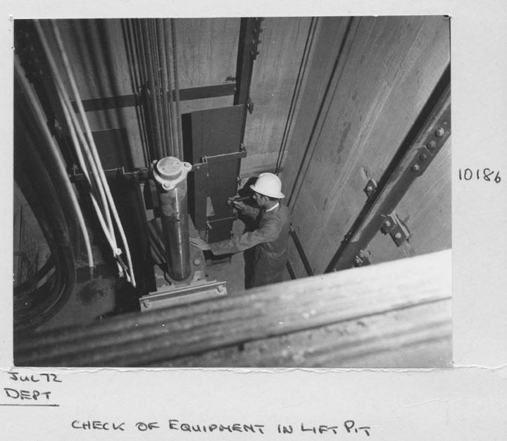 Construction of the State General Insurance Office (SGIO) building - Checking equipment in the lift pit - Brisbane, July 1972