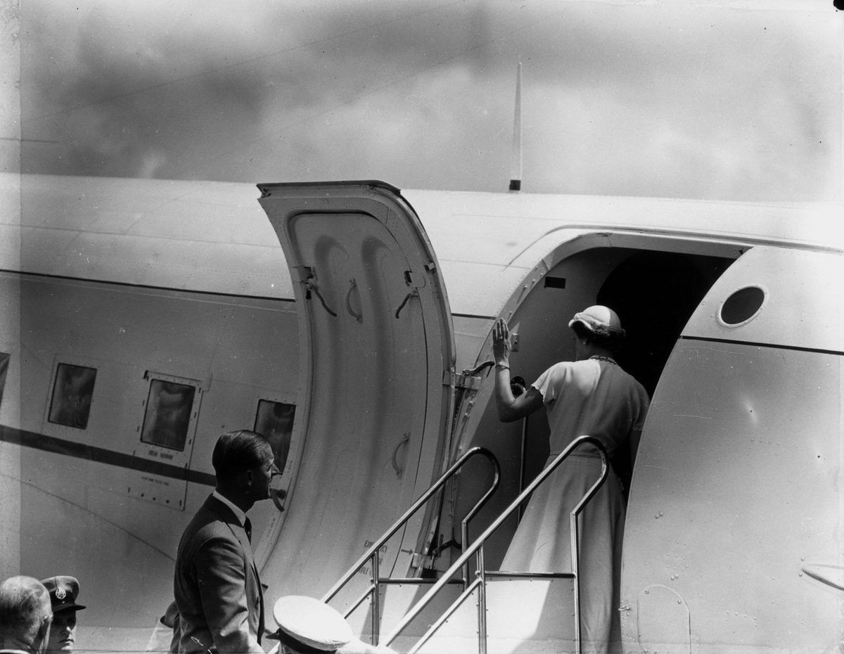 Queen Elizabeth II waves to well-wishers as she boards an aeroplane during her visit in March 1954