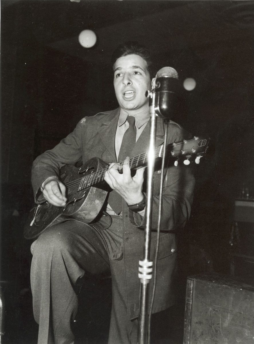 American soldier singing and playing guitar in performance with the U.S. Army Band in Brisbane
