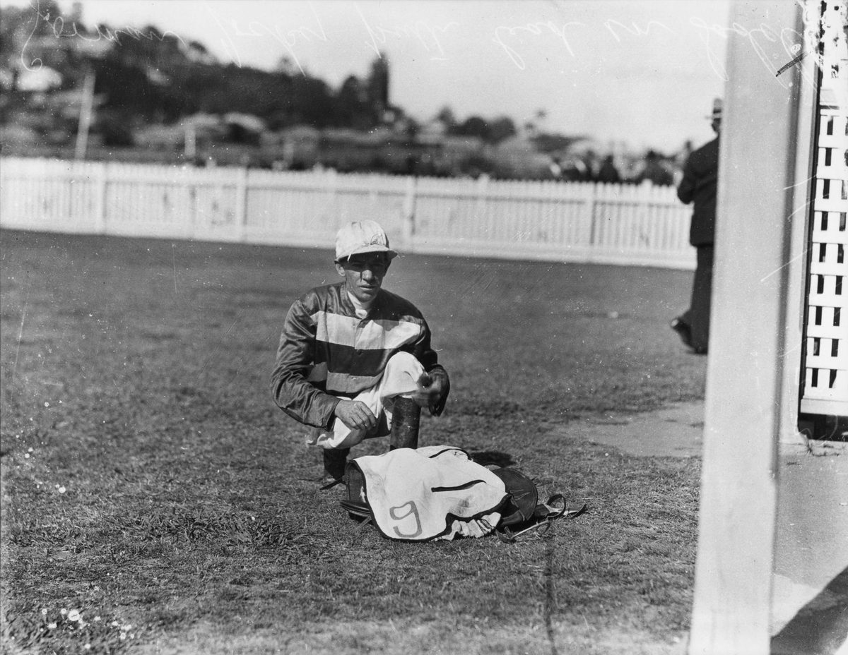 Jockey Jim Gorman is putting lead in his saddle before a race, Brisbane, 1933