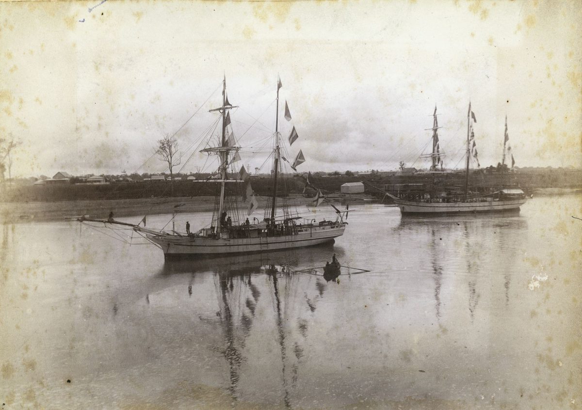 Schooner on the river with sails down and signal flags flying