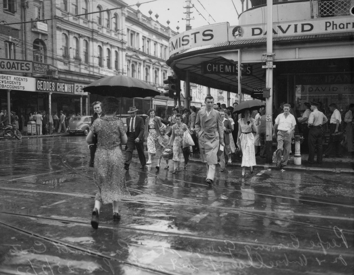 People crossing George Street in the rain, Brisbane, 1952