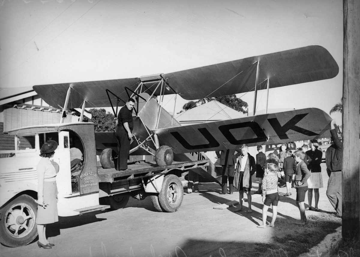 VH-UOK biplane being loaded onto a carrier's truck, 1939