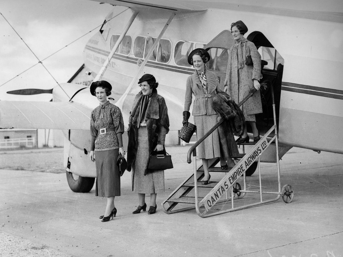 Fashion models posing with Qantas Empire Airways plane, Brisbane, 1936