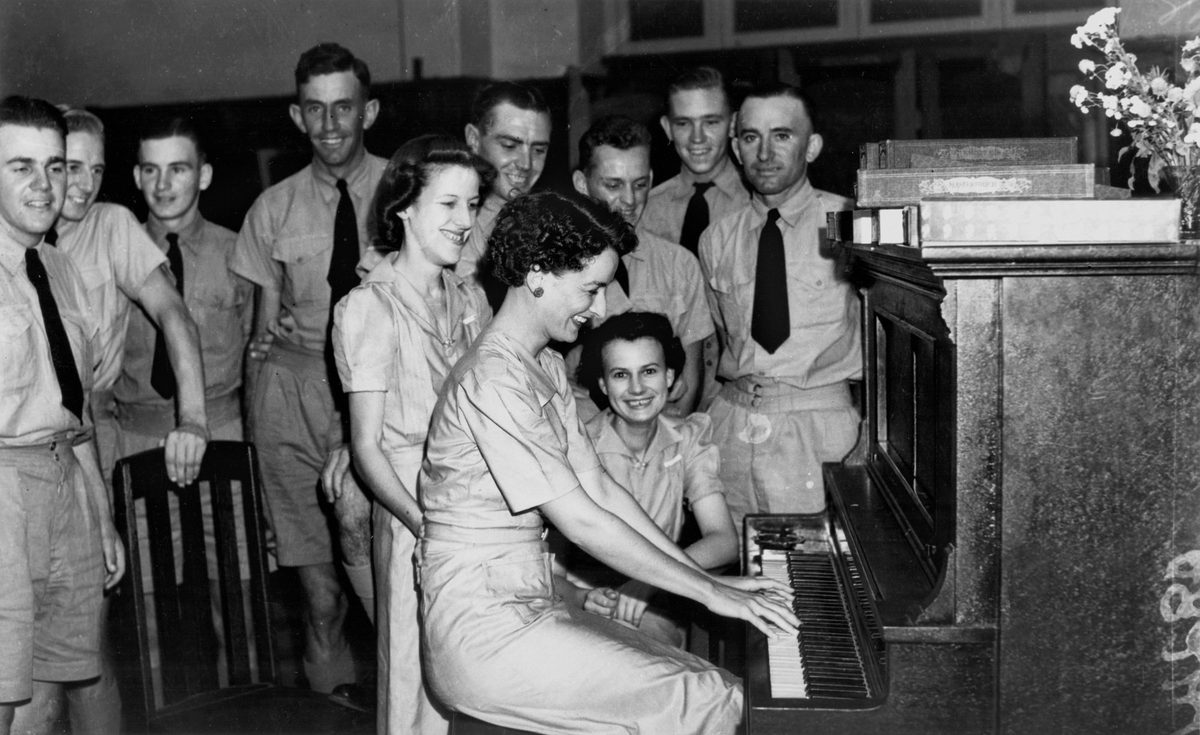 Enjoying a sing-along around the piano at tearooms in George Street Brisbane, January 1942