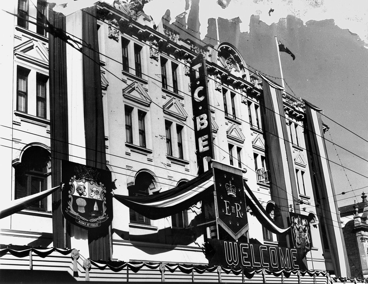 Queensland's Coat of Arms and the Royal Coat of Arms are part of the decorations on the T. C. Beirne building, 1954