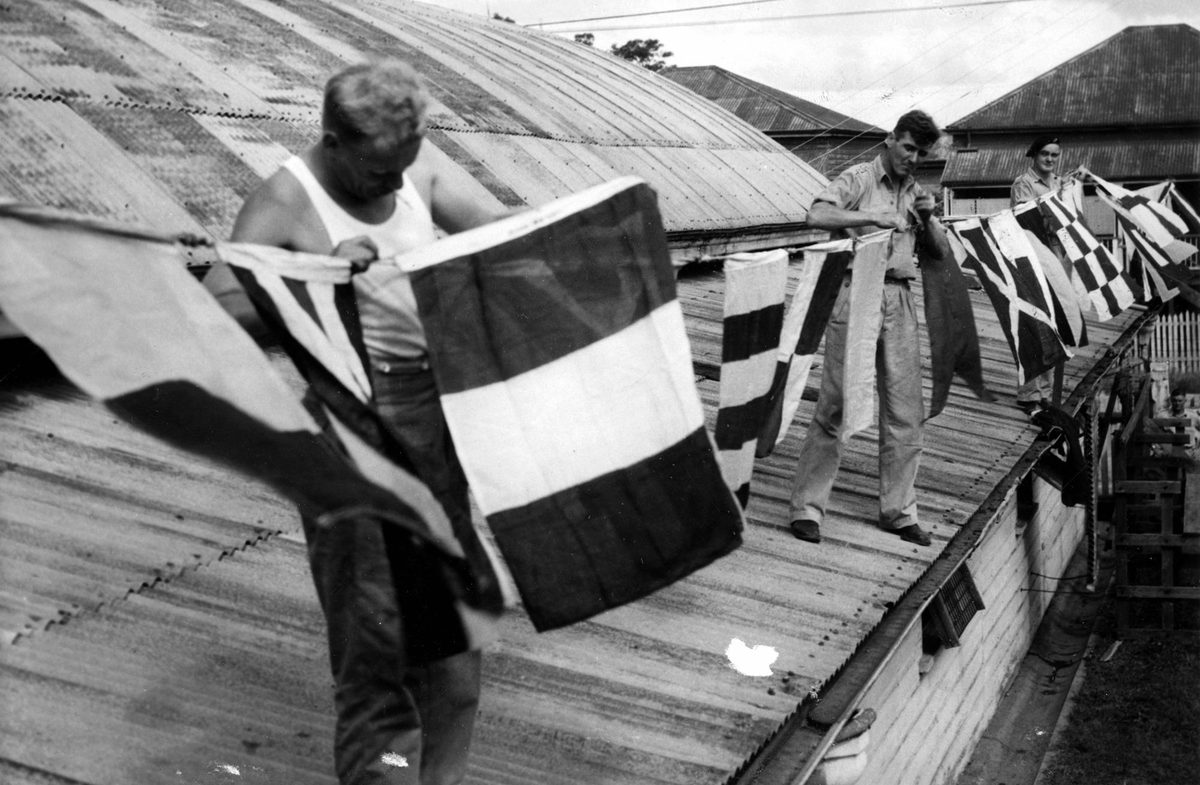 Workmen decorate their work building with colourful flags, ready for the Royal Visit in 1954
