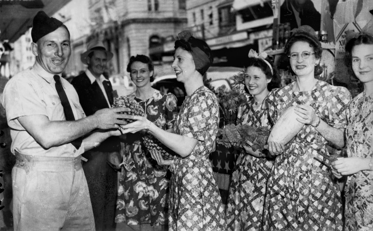 Liberty Week volunteers coaxing an airman into buying a pineapple, Queen Street Brisbane, November 1941