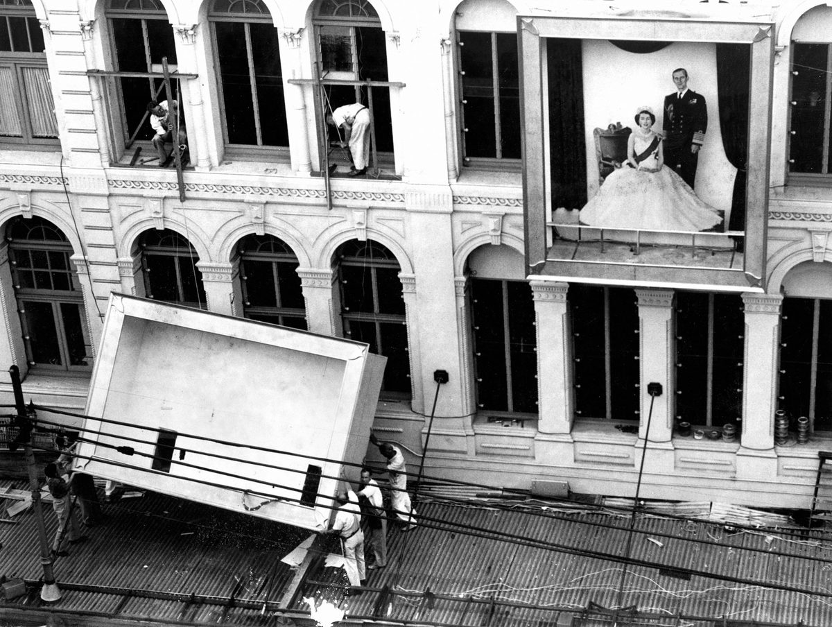 Workmen removing decorations from the Allan and Stark building after the Royal Tour in 1954
