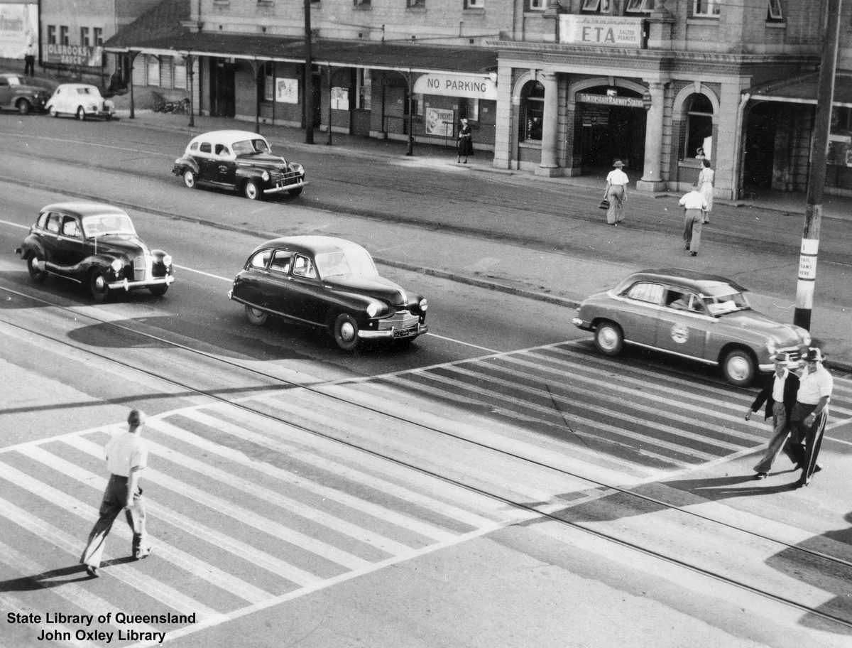 Pedestrians crossing the road in front of South Brisbane Railway Station, 1954