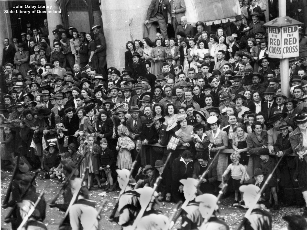 Crowd on Queen Street, Brisbane, watches the Seventh Division troops pass by the General Post Office