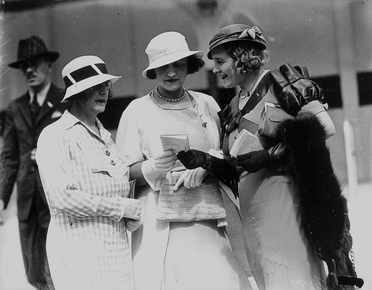 Three women studying the form guide at Ascot races, Brisbane, 2 December 1933