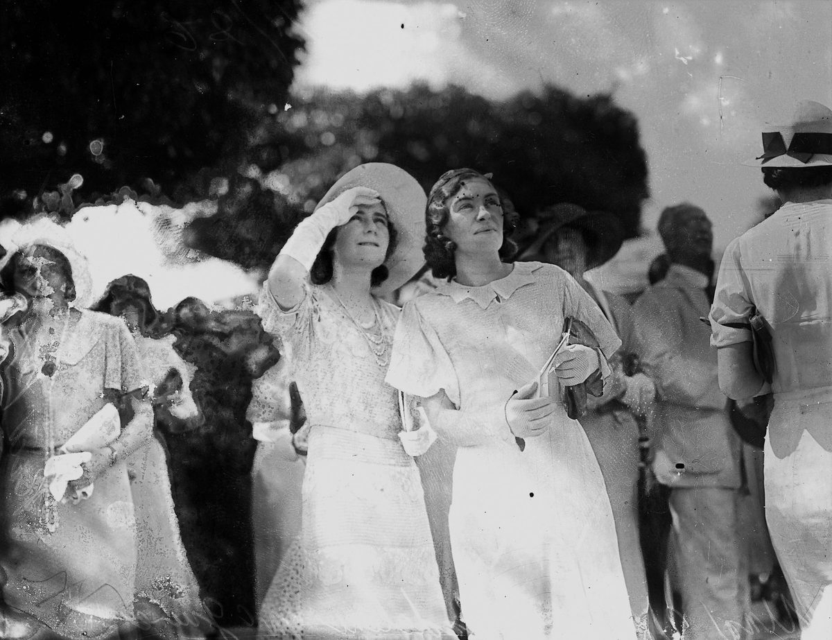 Una Vowles and Miss Madeline McGuire study the tote board at Ascot races, Brisbane, January 1933