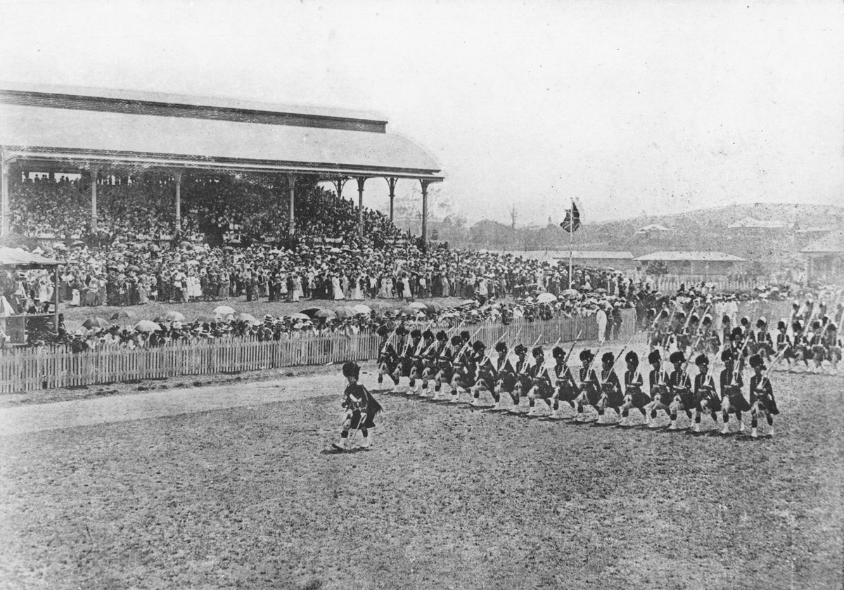 Highlanders march by as a crowd at Eagle Farm watch on, 1901