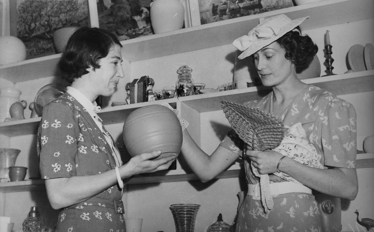 Miss Bess Hawkins admiring a pottery bowl in an art shop, 1940