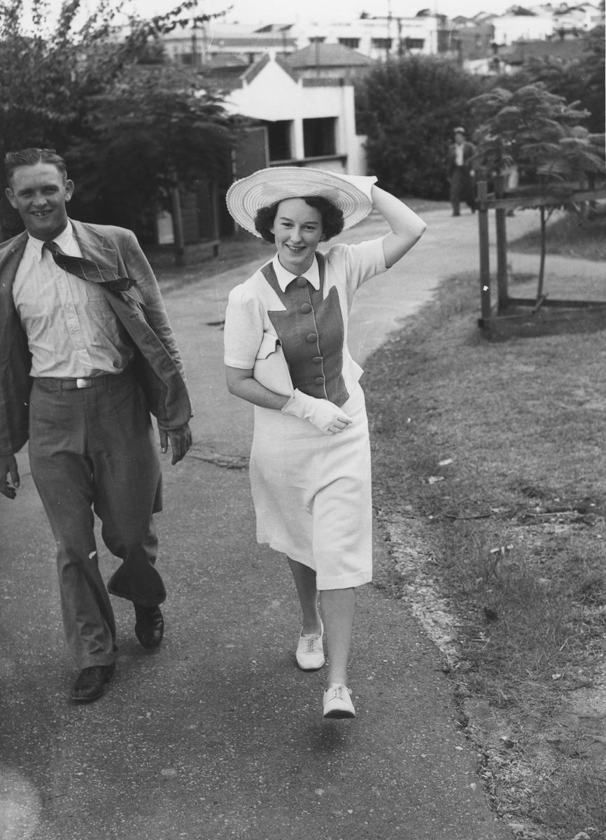 Couple walking along a path near the Brisbane Cricket ground, 1941