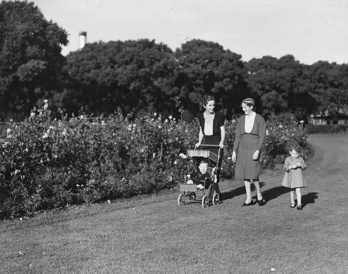 Mrs. P. Campbell pushing Andrew, in pram, and Mrs. R. Hildebrandt and Beverley Hildebrandt strolling in New Farm Park, Brisbane, 1939