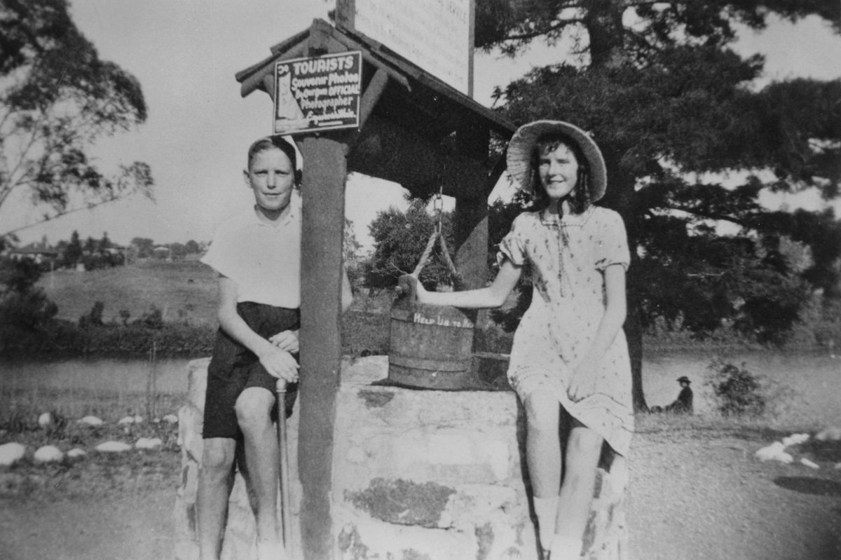 Two young people pose at Ye Olde Wishing Well at the entrance to Lone Pine Koala Sanctuary, Fig Tree Pocket, 1938