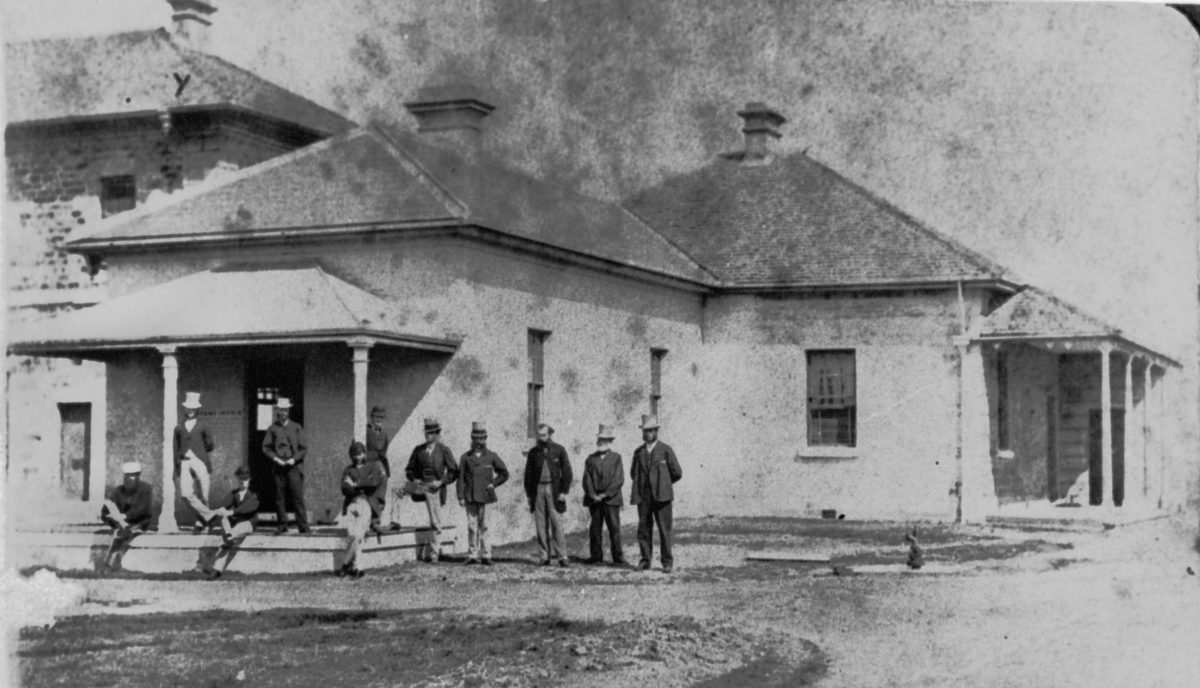 Group of men standing outside the first Military Barracks in Brisbane, 1872