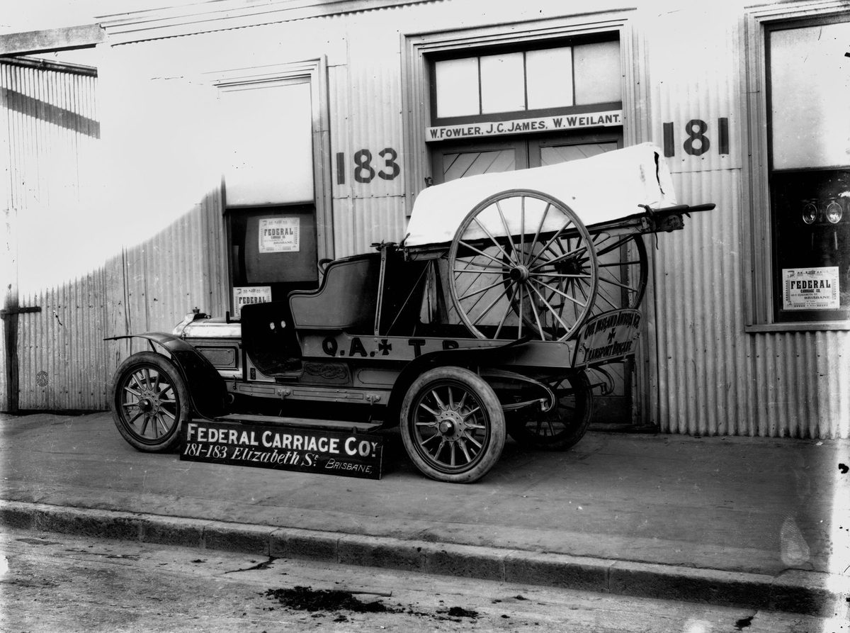Early motor ambulance and wheeled stretcher in front of the Federal Carriage Co. premises, Brisbane, 1912